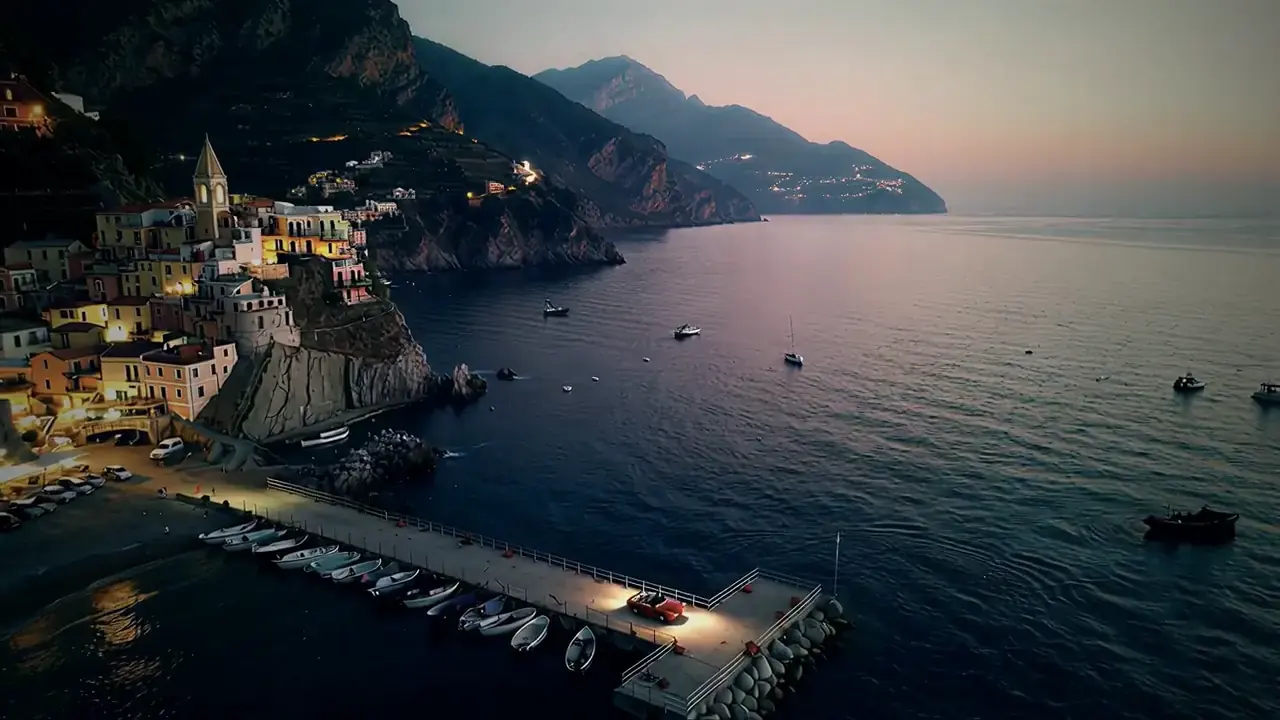 Dusk over the coast: village lights, the pier and the shoreline stretching into the distance.